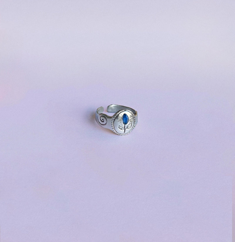 Chevalière RachaJewellery en argent, plateau ovale floral, saphir bleu et spirales latérales, anneau ajustable